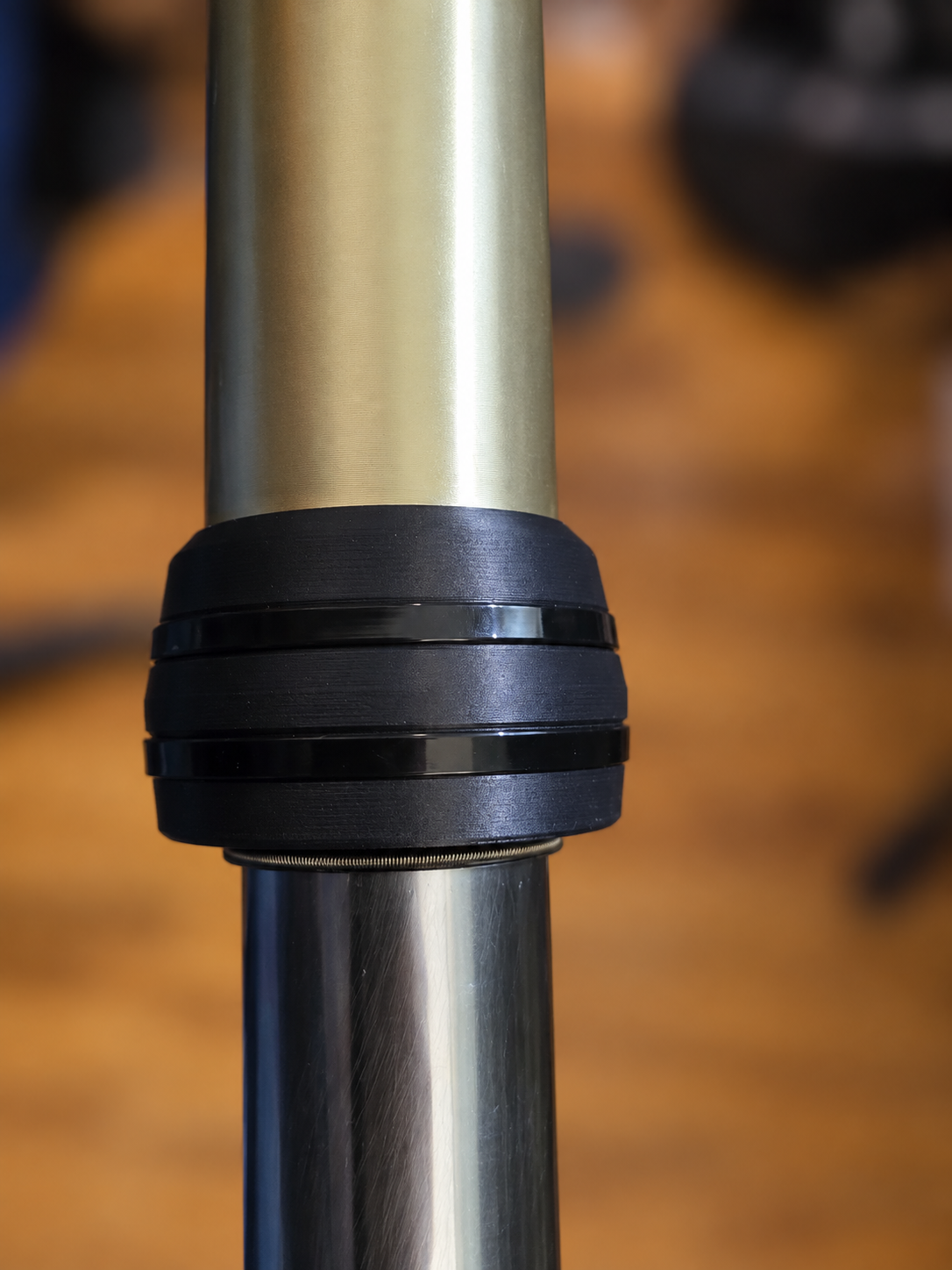 Plain-black M4 Enduro 43mm KYB fork guard installed on the outer fork housing and secured with two plain black zip ties. Second installation view with the lower chrome tube visible. No white logo. Background blurred.