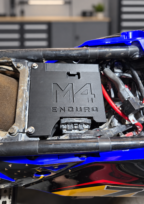 Close-up of the M4 Enduro ECU relocate enclosure installed under the seat of a Yamaha Ténéré 700, with a clean, softly blurred workshop background.