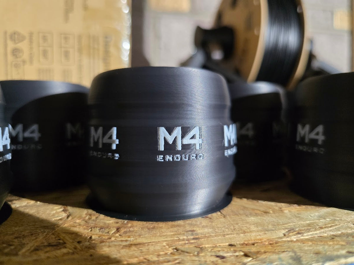 Black M4 Enduro fork guards with white branding for 48 mm KYB forks, shown on a workbench.
